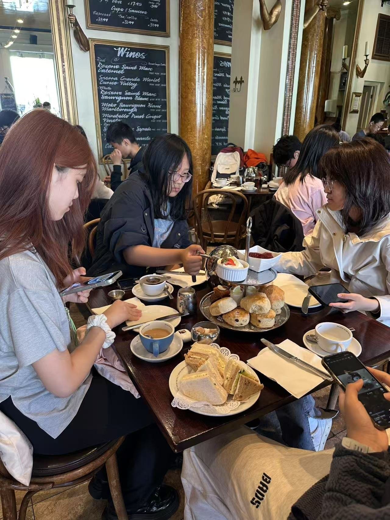 Students sharing afternoon tea, with scones and cakes on the table