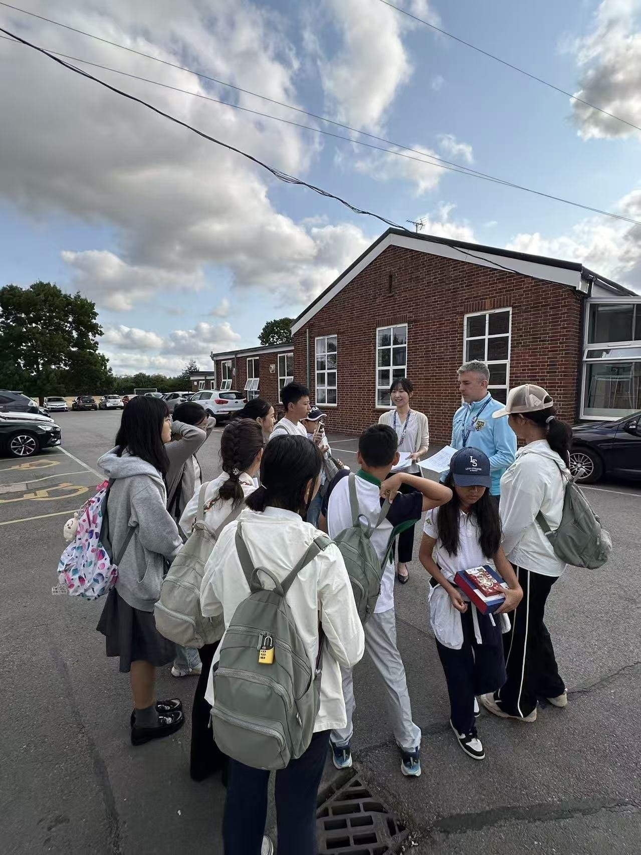 A group of students with rucksacks gathering outside a school building on arrival