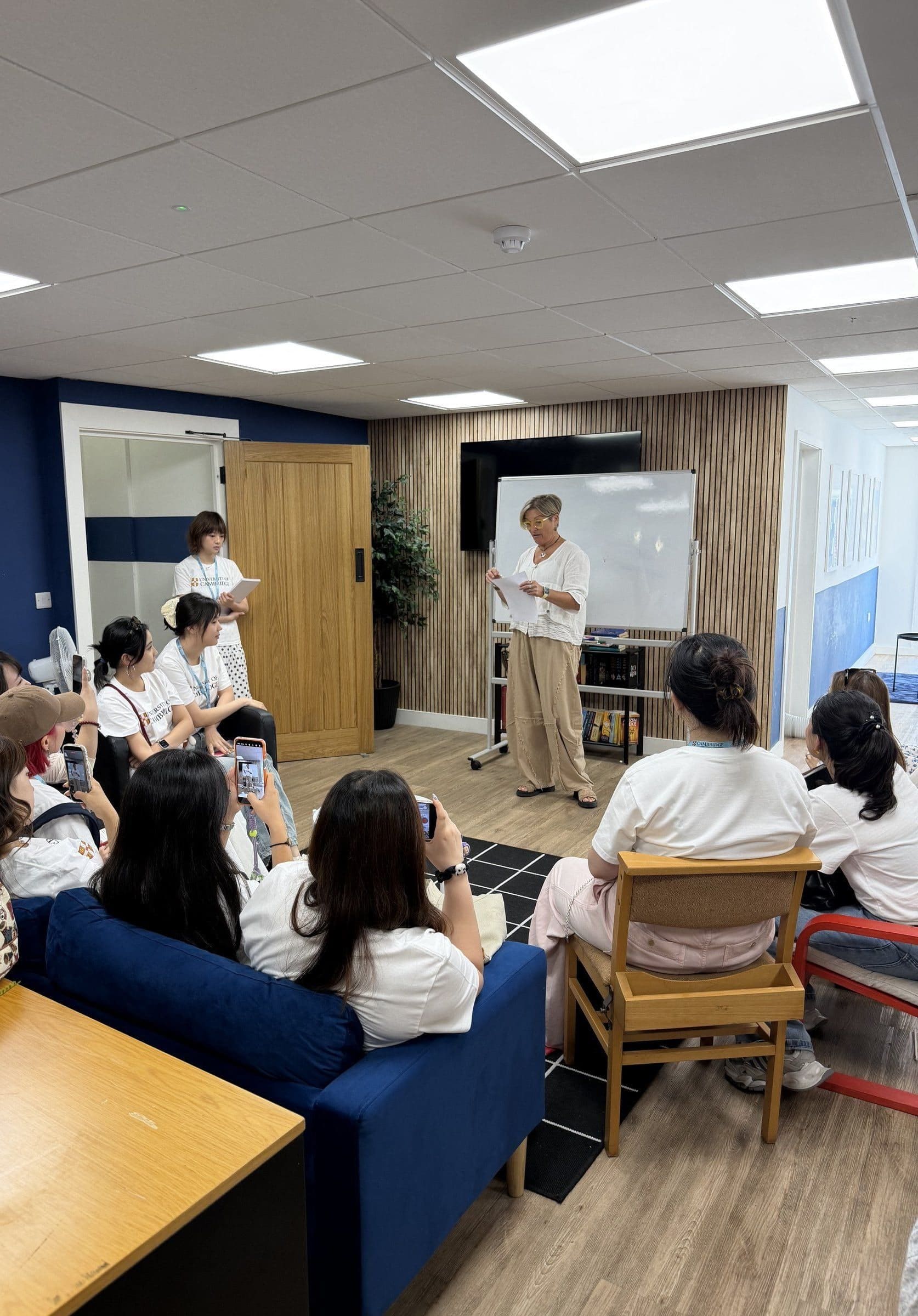 Teachers on sofas and chairs in a workshop led by a UK language teacher standing at a whiteboard