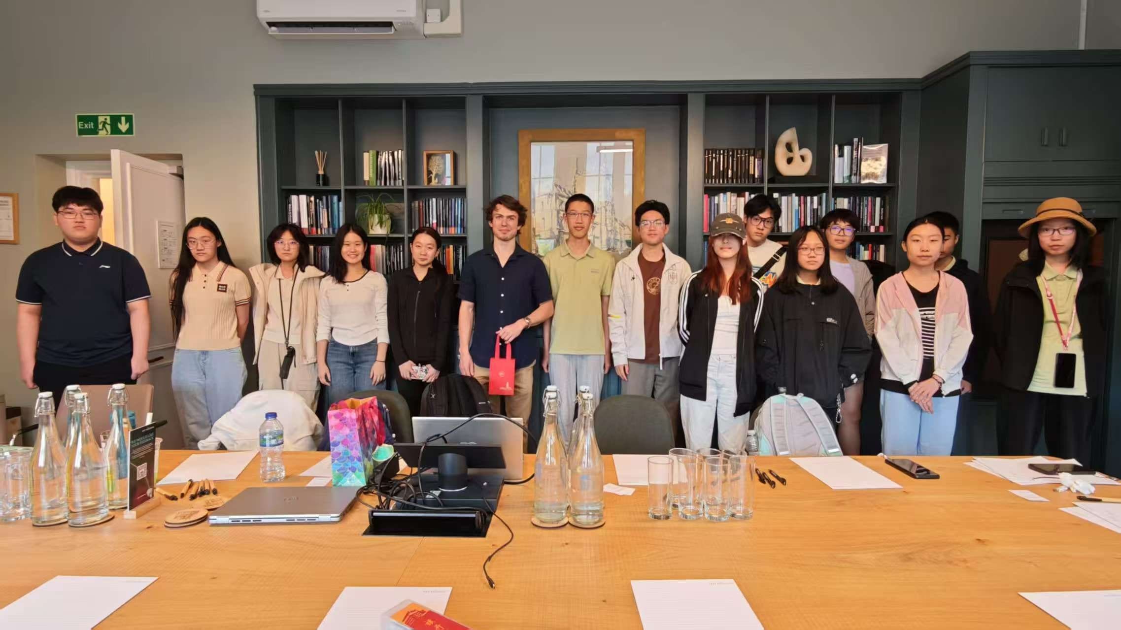 The group standing together with their tutors in a book-lined seminar room