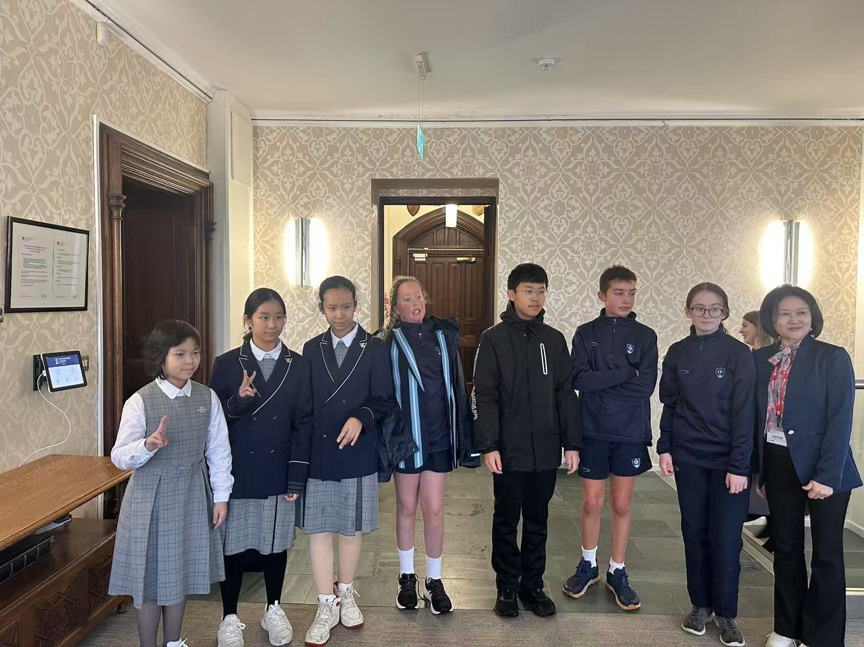 Visiting students and their UK buddies, each group in its own school uniform, in the entrance hall at Windermere School
